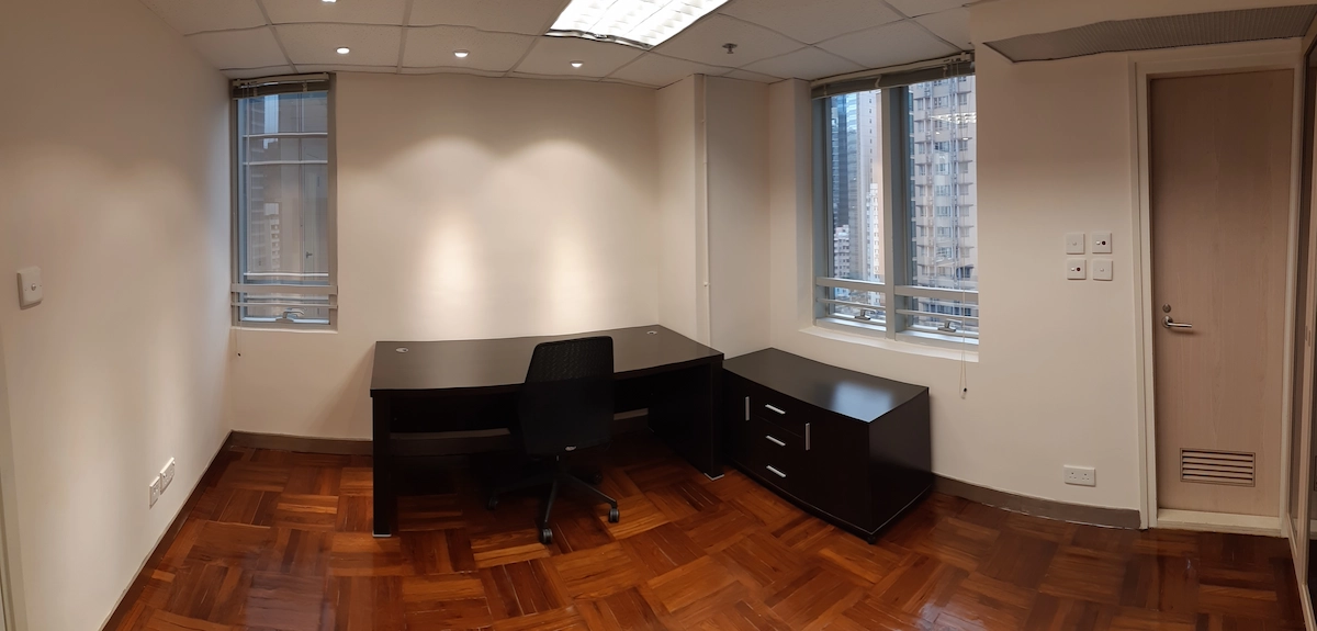 Small office in Central with a dark desk, chair, drawers, parquet floor, two windows, and beige walls.