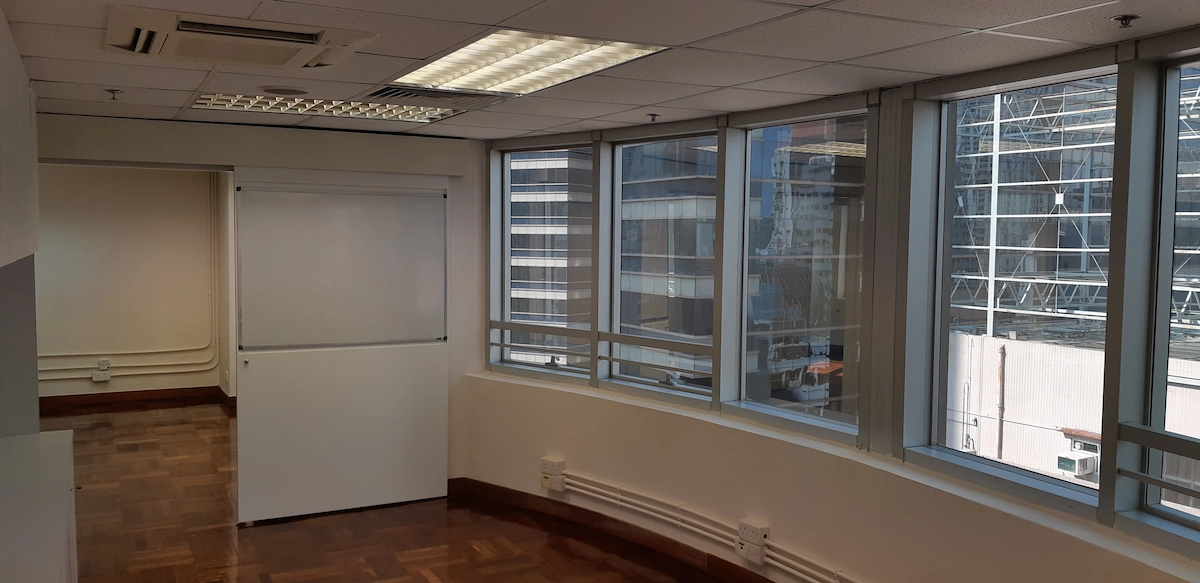Empty office in Central with large windows, white walls, wooden flooring, and view of Queen’s Road Central scaffolding.