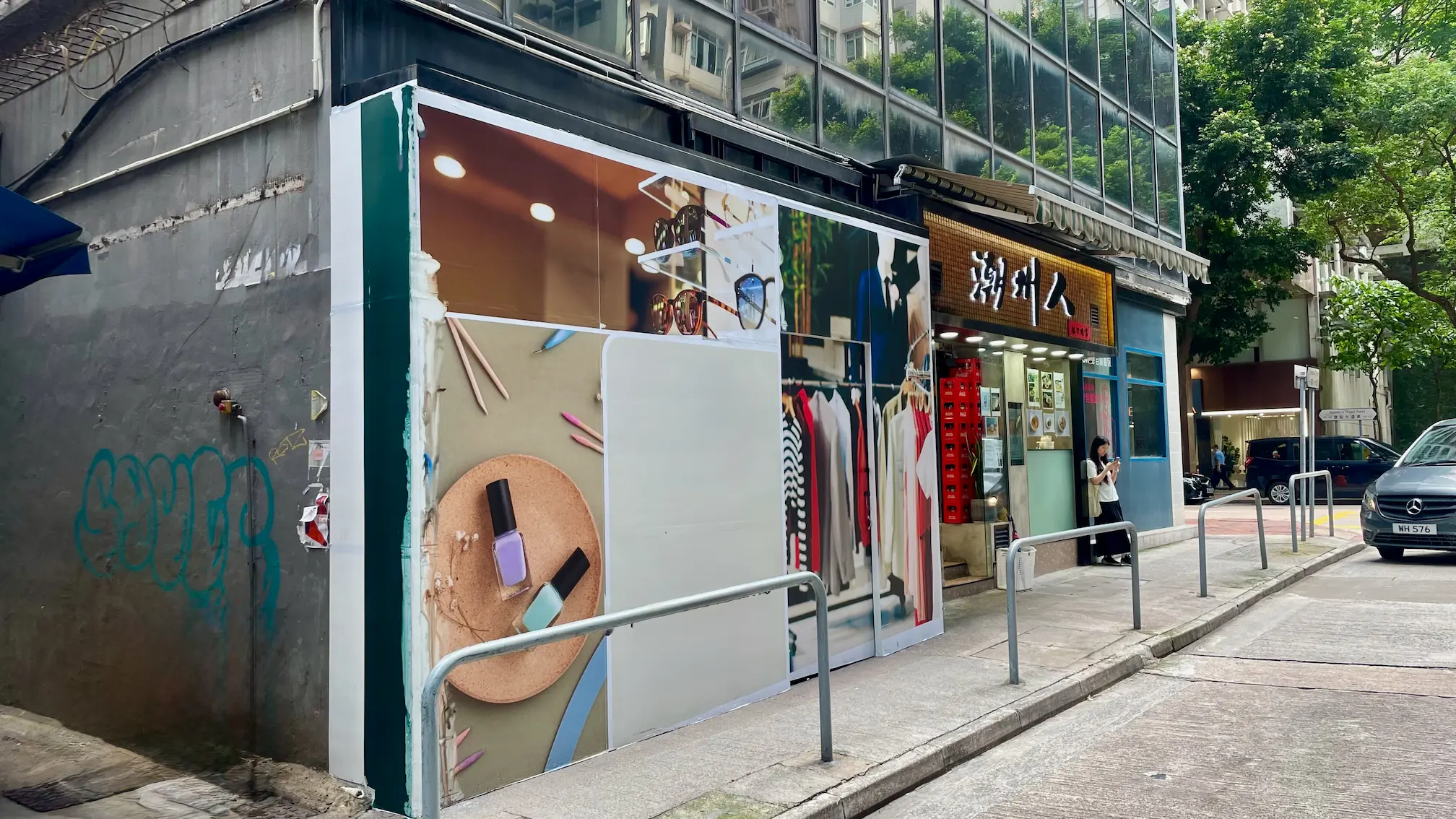 灣仔舖位。皇后大道東一個舖位被大型服裝海報遮蓋,旁為其他店舖及泊車位。