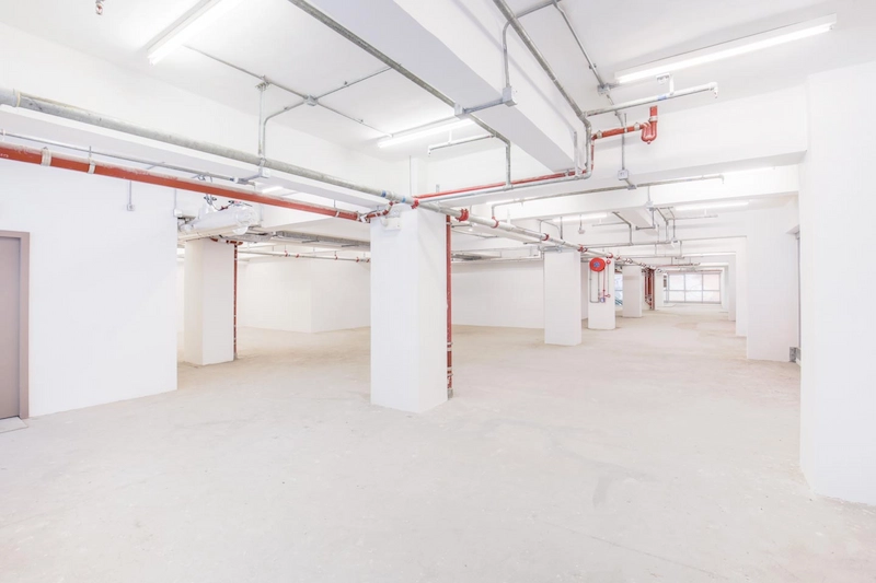 Shop on Hennessy Road, Causeway Bay. Spacious empty white basement featuring exposed ceiling pipes and bright overhead lights.