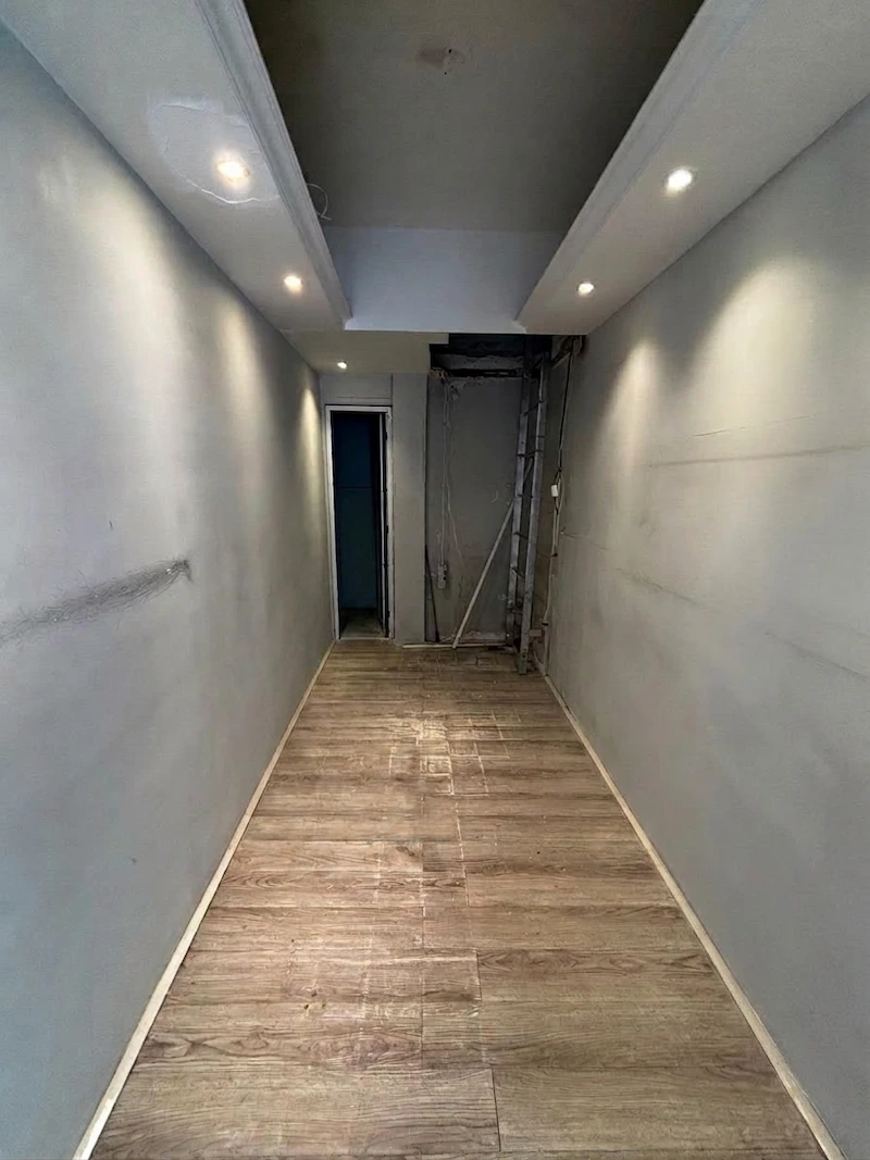 Shop on Peel Street, Central. Narrow hallway with light gray walls, wood-like flooring, ceiling lights, and an open doorway and Peel Street.