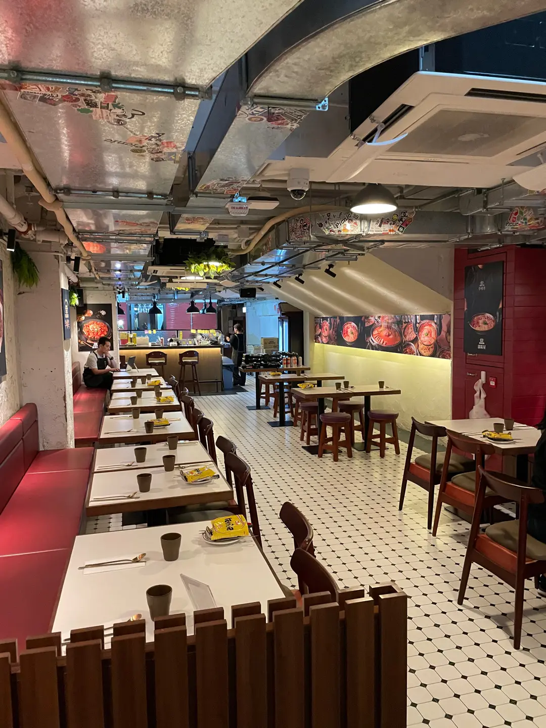 Restaurant interior on Hollywood Road Central with red booths white tables wooden chairs tiled floor and wall art.