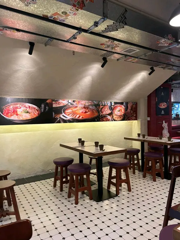 Interior of a restaurant on Hollywood Road in Central with wooden stools, tiled floor, wall art, and ceiling spotlights.