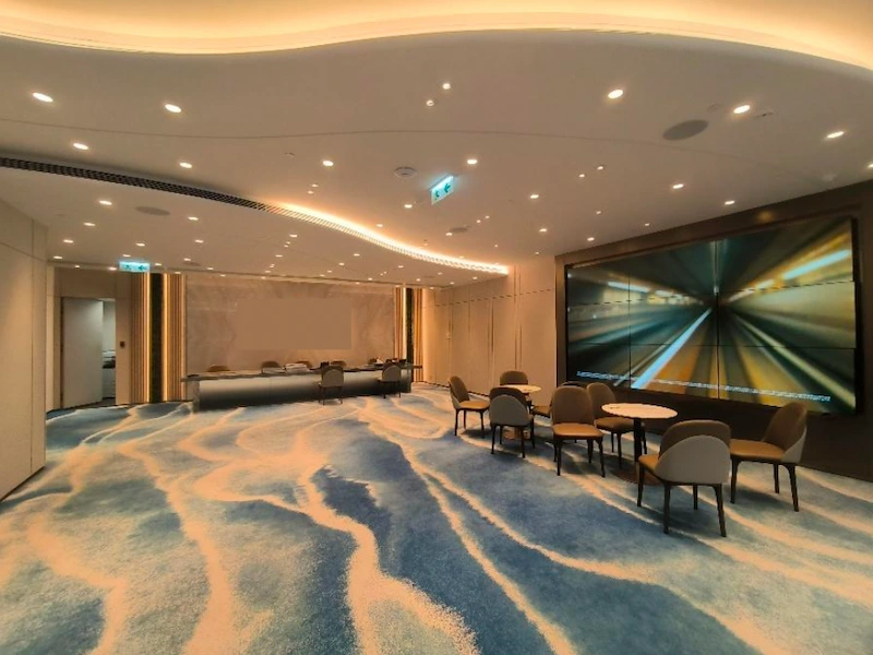 Shop on Mody Road, Tsim Sha Tsui. Meeting room with blue carpet, round tables, large screen and recessed lighting.