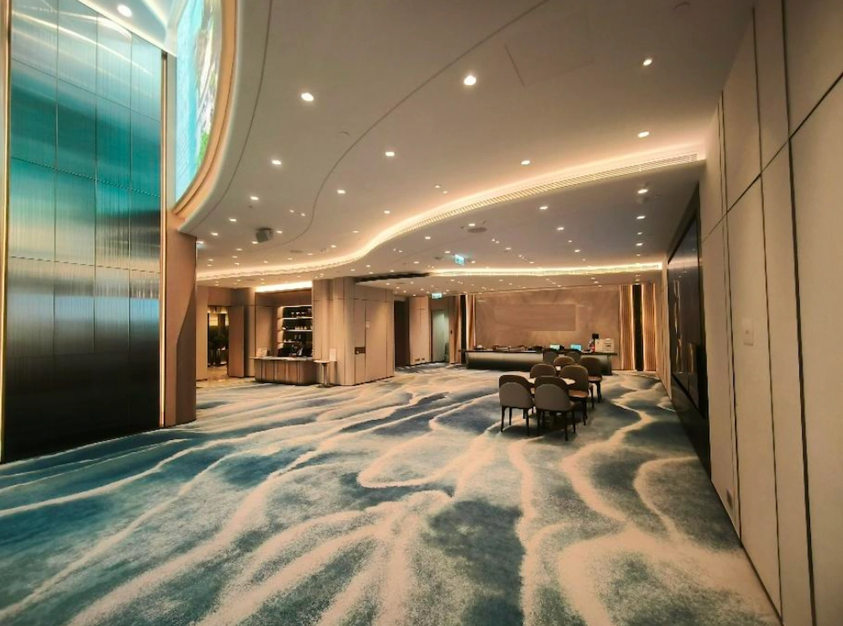 Modern room on Mody Road, Tsim Sha Tsui with blue carpet, round chairs, ceiling lights, and tall windows.