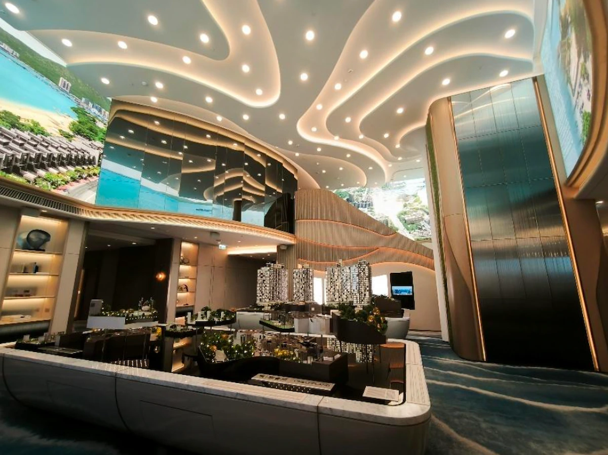 Lobby on Mody Road in Tsim Sha Tsui with curved ceiling lights, large mirrors, plants, and digital landscape screens.