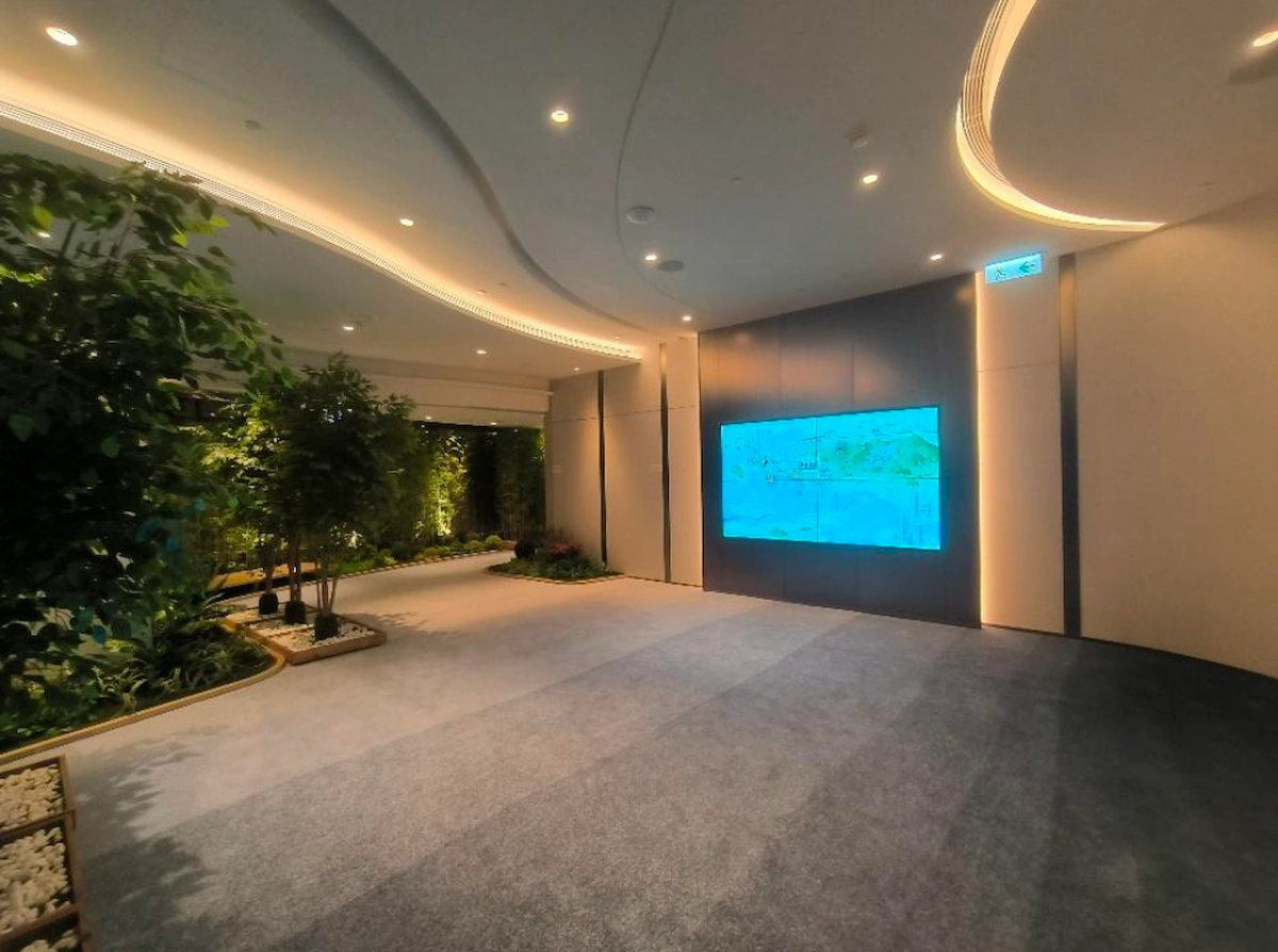 Modern interior on Mody Road, Tsim Sha Tsui, carpeting throughout, indoor plants on left, large screen display on right.