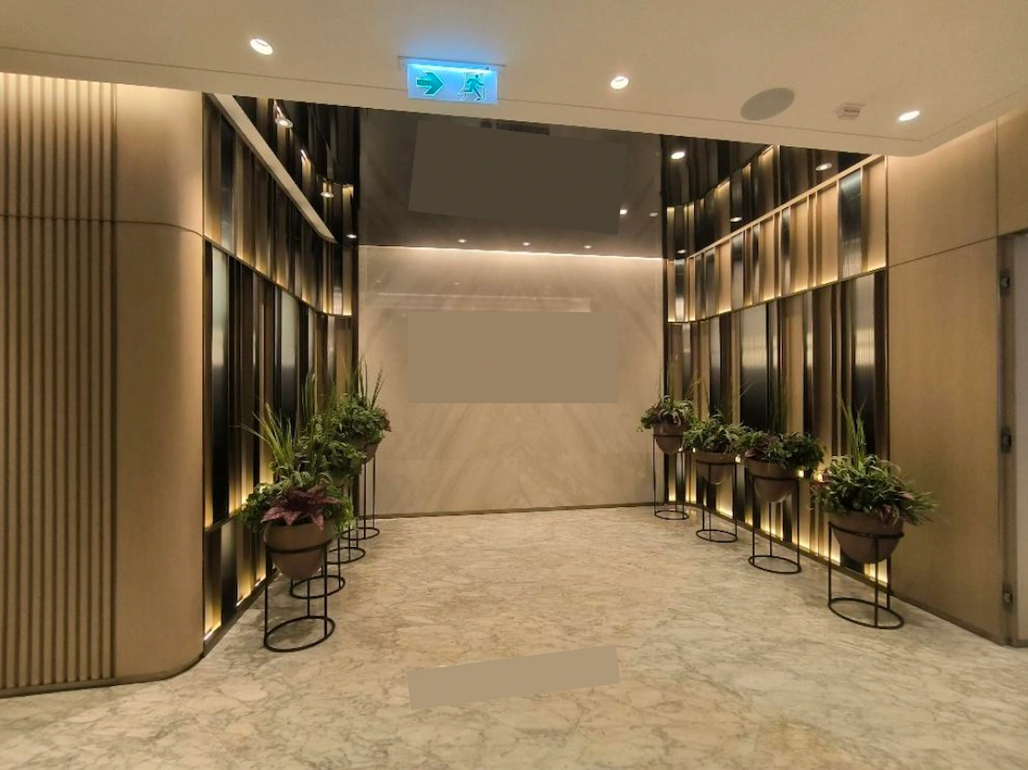 Hallway on Mody Road, Tsim Sha Tsui, with marble floors, wood panel walls, potted plants, and an emergency exit sign.