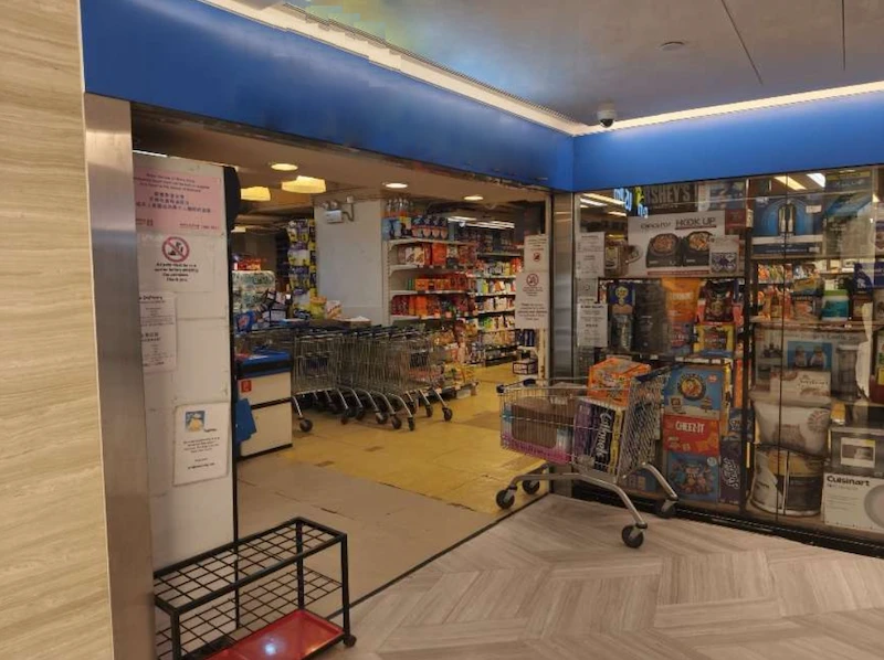 Shop on Queen's Road Central, Central. Grocery store entrance on Queen’s Road Central with shopping carts, shelves, and a blue sign above the door.