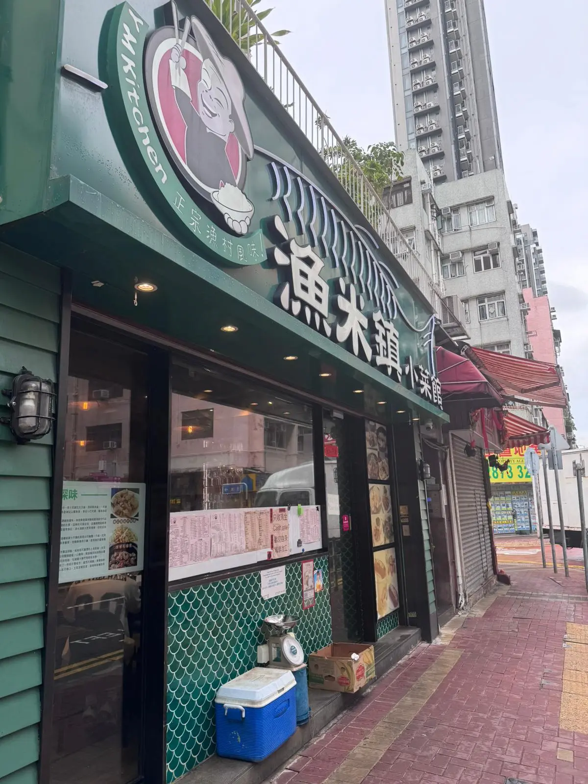 Green restaurant with pig logo, menu boards, and coolers on sidewalk on Ap Lei Chau Main Street.