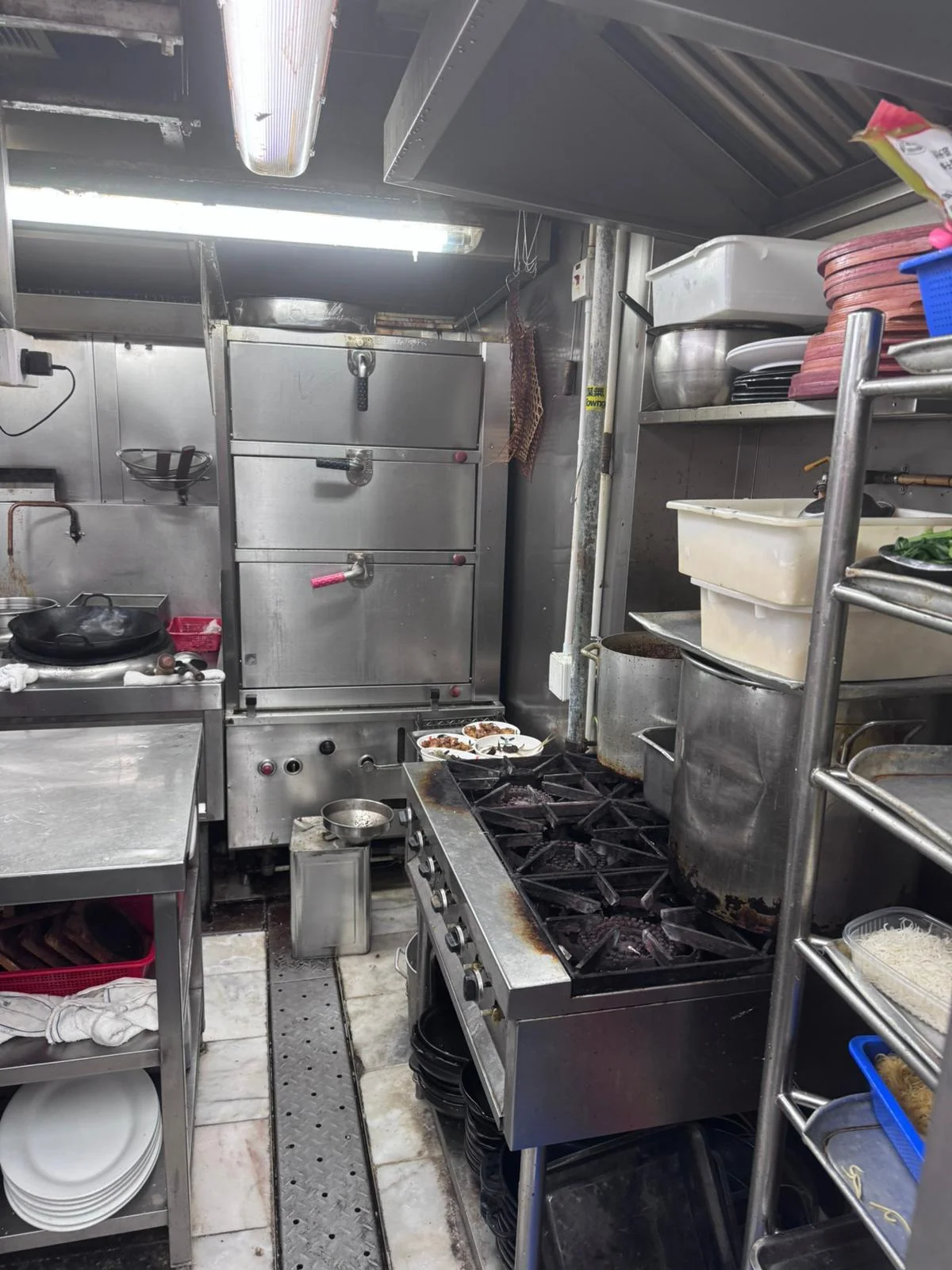 Small commercial kitchen on Ap Lei Chau Main Street featuring a gas stove, metal shelving, and assorted storage containers.