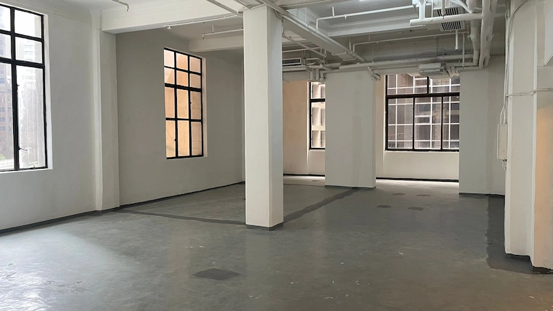 Shop on Pedder Street, Central. Empty room with large windows, white walls, exposed pipes, gray floor and natural light.
