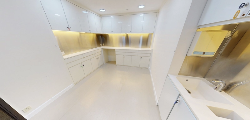 Office on Des Voeux Road Central, Central. Kitchenette with white cabinets, stainless steel backsplash, and under-cabinet lighting.