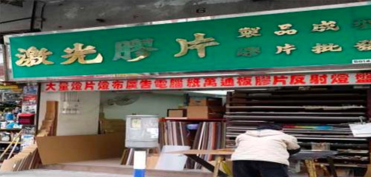A person works outside a shop on Reclamation Street, beneath a green sign displaying Chinese characters.
