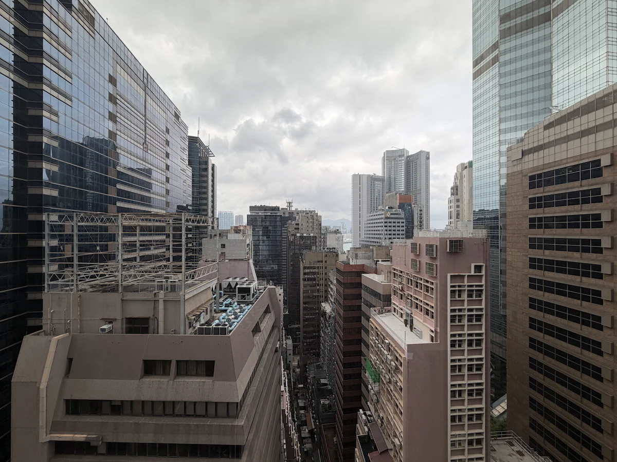 Tall office buildings in Central above Queen’s Road Central under a cloudy sky.