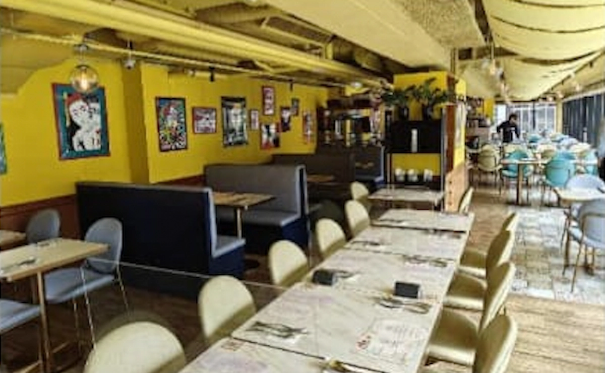 威靈頓街一間咖啡店牆身黃色，設現代藝術裝潢、卡座及長型共用餐桌。