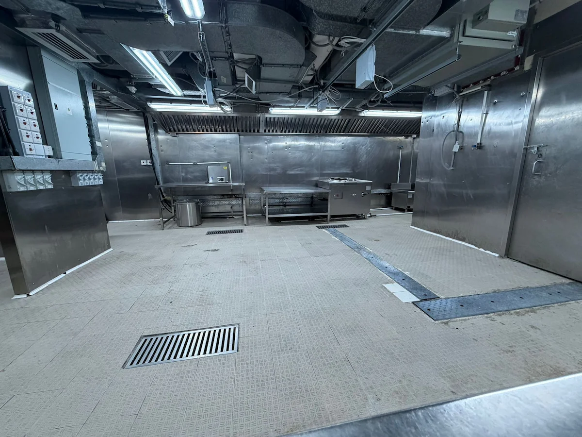 中環威靈頓街一個工業不鏽鋼廚房設空置枱面、洗手盆及地磚，風管外露。