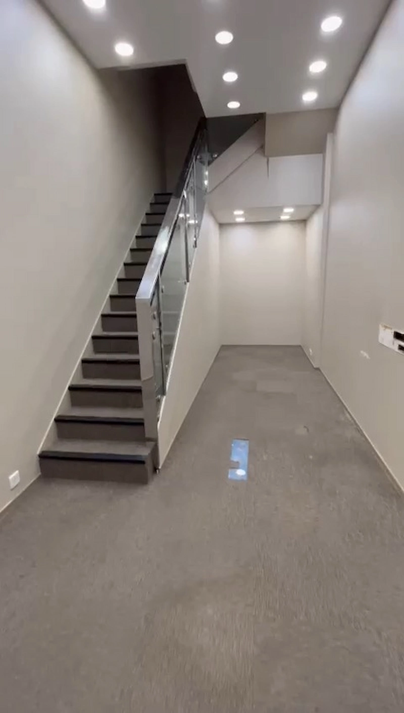 Shop on Lan Fong Road, Causeway Bay. Empty, narrow room with gray carpet, recessed lighting, and a glass-railed staircase on the left.