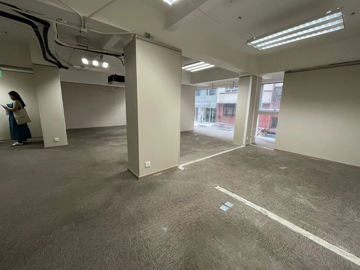 Empty office space on Lan Fong Road featuring carpeted floors, large windows, and a person standing in the corner.