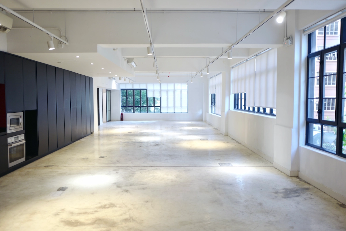 Empty room in Sheung Wan featuring white walls, large windows, black cabinets, and a built-in oven on the left side.