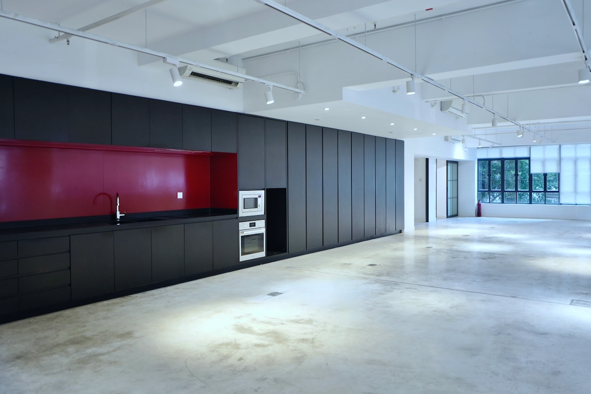 Modern kitchen in Sheung Wan featuring black cabinets, red backsplash, built-in appliances, and an open floor plan.