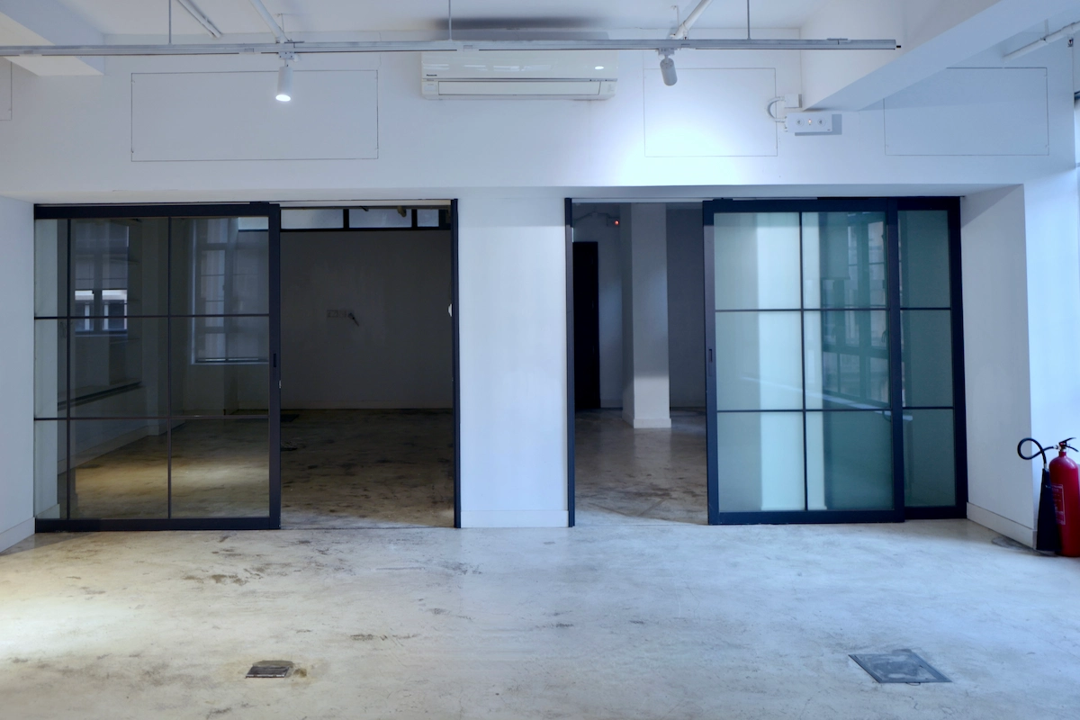 Empty room in Sheung Wan featuring two large glass sliding doors, white walls, and a fire extinguisher on the right side.