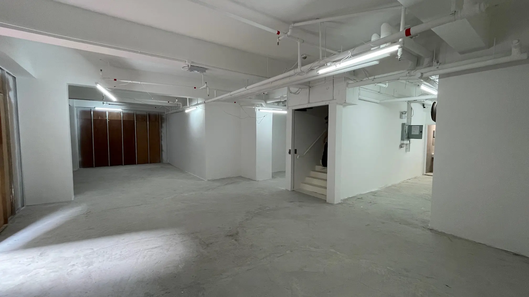 Industrial area on Queen’s Road East, Wan Chai, featuring white walls, exposed pipes, and a stairway leading upward.