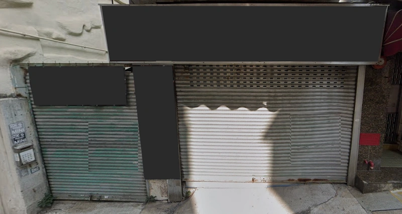 Shop on Tsun Yuen Street, Happy Valley. Two closed metal rolling shutters with blacked out signs above and shadows on the ground.