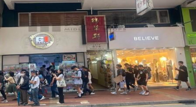 Shop on Sai Yeung Choi Street, Mong Kok. People walk by G.I. Gatcha and BELIEVE, some are wearing masks.