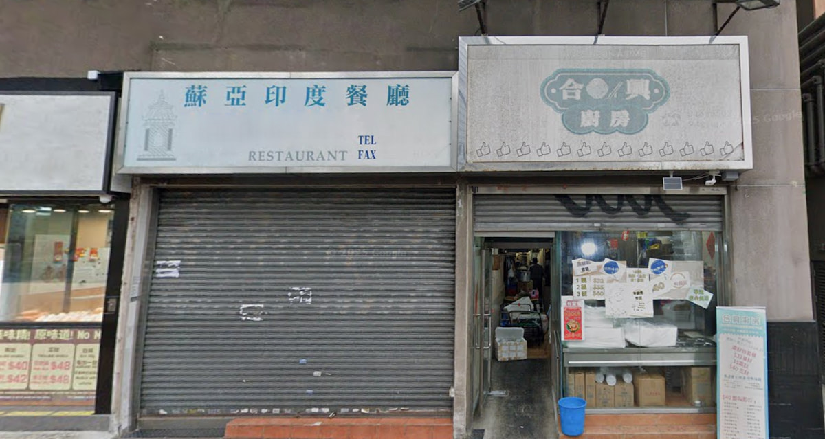 A closed restaurant on Cheung Sha Wan Road next to an open eatery with visible tables, chairs, and kitchen items inside.