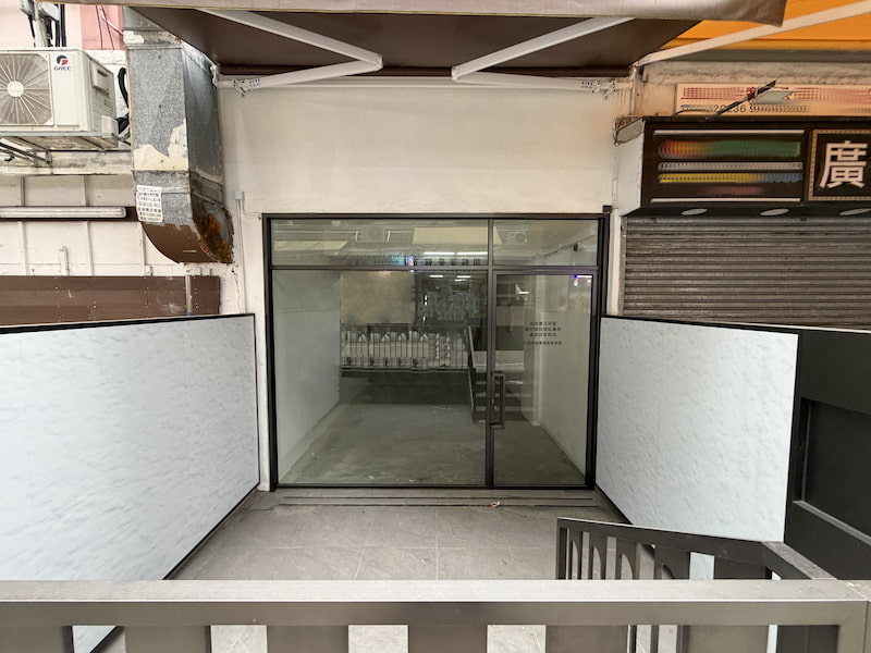 Restaurant space on Sung Chi Street, To Kwa Wan. Vacant storefront with glass doors and staircase, situated between other businesses.