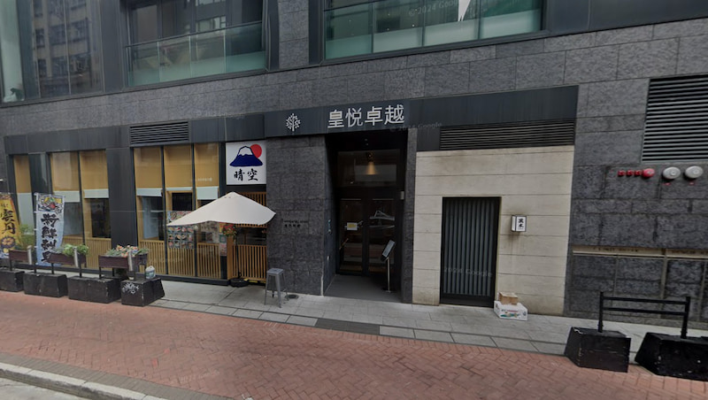 Shop on Kimberley Street, Tsim Sha Tsui. Modern building facade with restaurant entrance, Chinese signage, and sidewalk in Tsim Sha Tsui.