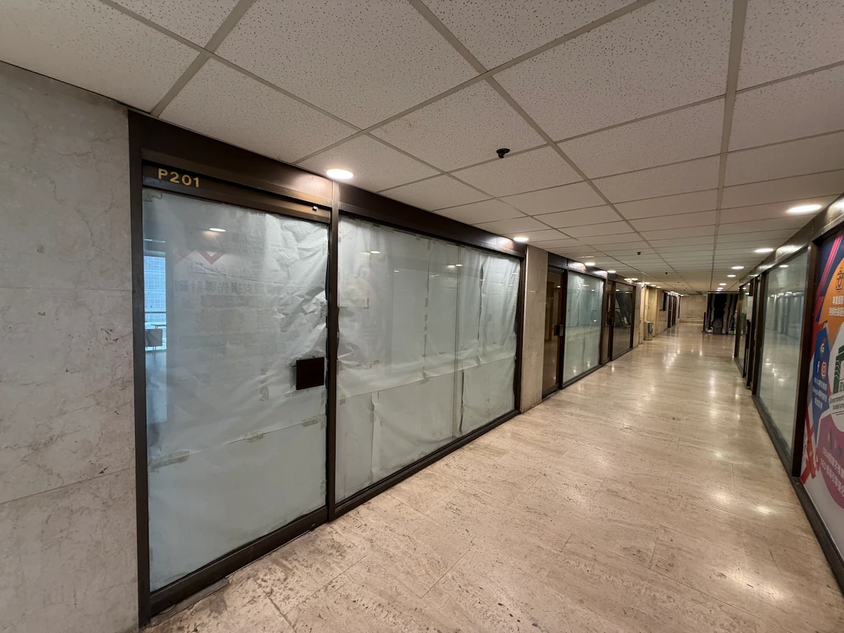 Hallway on Lok Ku Road, Sheung Wan with closed office spaces; one door features frosted glass, paper, and label P201.
