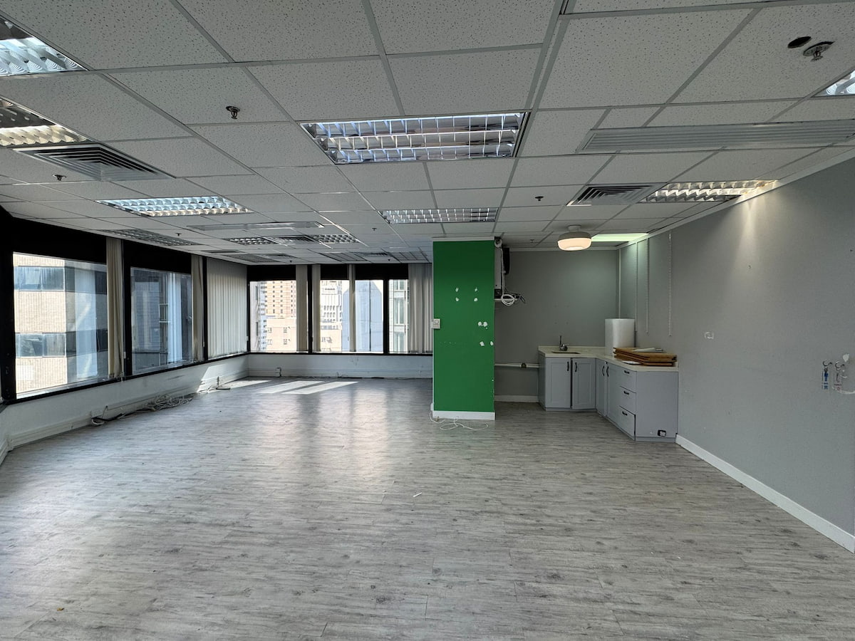 Office space on Leighton Road with large windows, gray floors, a green accent wall, and a kitchenette.