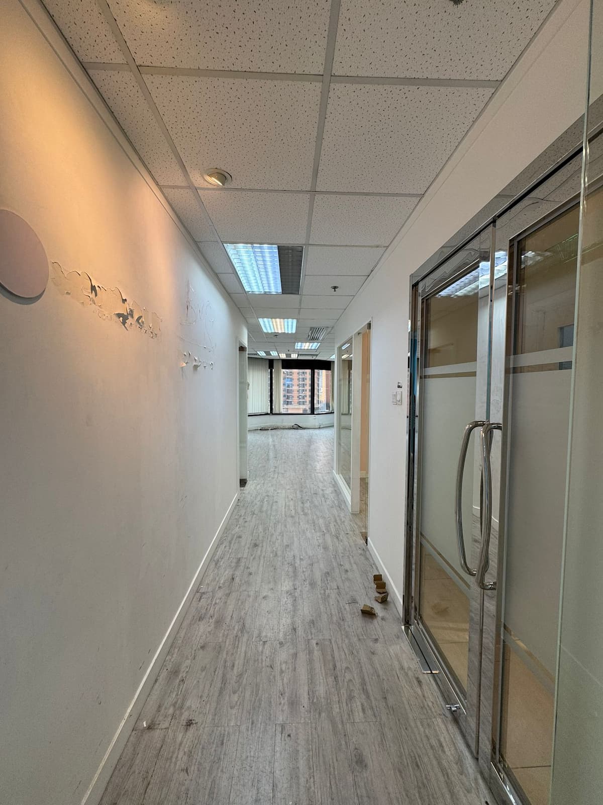 Hallway with light wood floors, white walls, and glass doors overlooking buildings near Leighton Road in Causeway Bay.