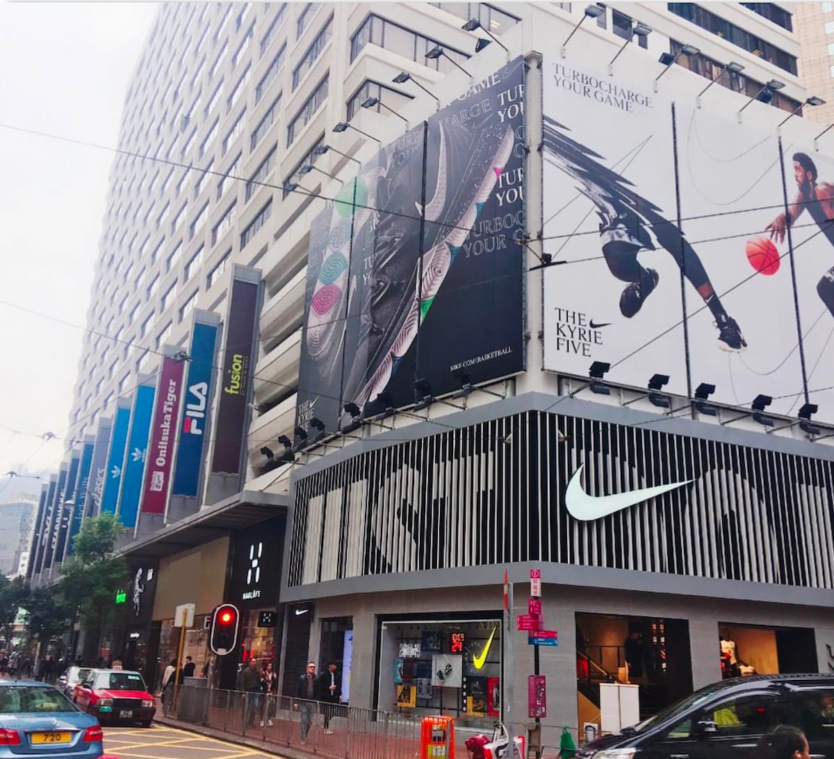 Nike store on Leighton Road, Causeway Bay, with large billboards and pedestrians near city brand logos.