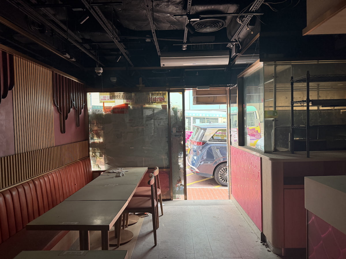 A dimly lit restaurant on Lan Fong Road, Causeway Bay, with tables near an open door and parked cars visible outside.
