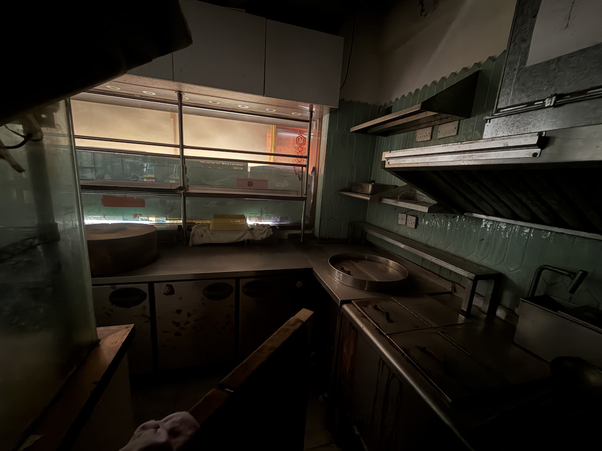 Empty commercial kitchen on Lan Fong Road with stainless steel counters and a window letting in some light.