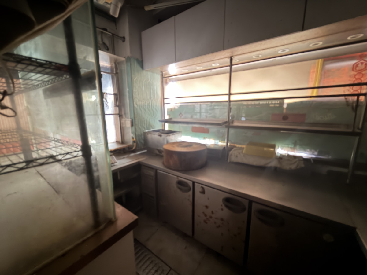 A kitchen with subdued lighting, metal shelving, and food containers, reflecting Lan Fong Road in Causeway Bay.