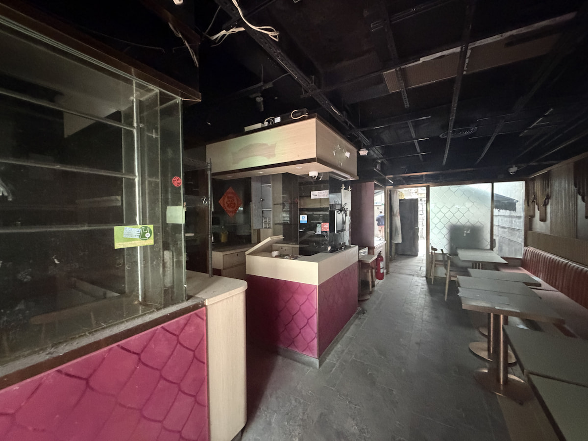 A restaurant on Lan Fong Road with dim lighting, empty tables, a counter area, and visible ceiling pipes.