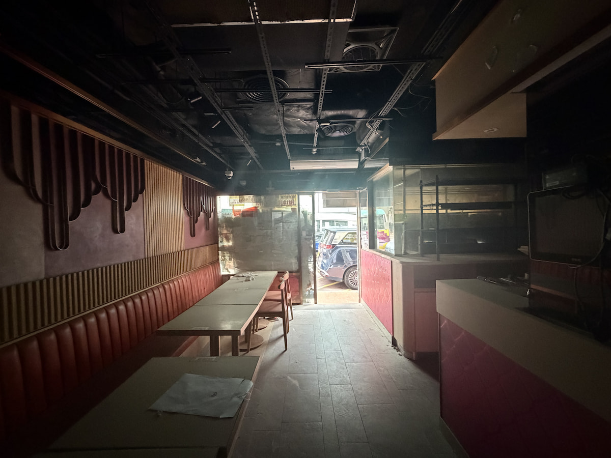 Empty restaurant in Causeway Bay with red seats and tables, entrance showing view of Lan Fong Road, dim lighting.