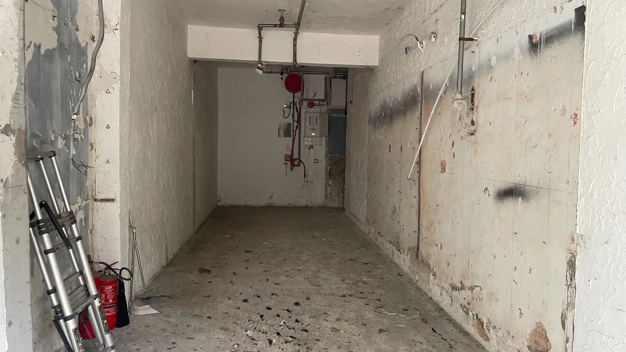 禮頓道一個空置窄身混凝土單位喉管外露，牆身油漆剝落，地上放有滅火筒。