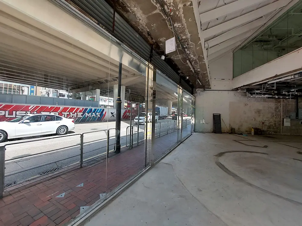 Vacant, unfinished commercial space on Leighton Road, Causeway Bay, with glass walls facing a street mural and traffic.