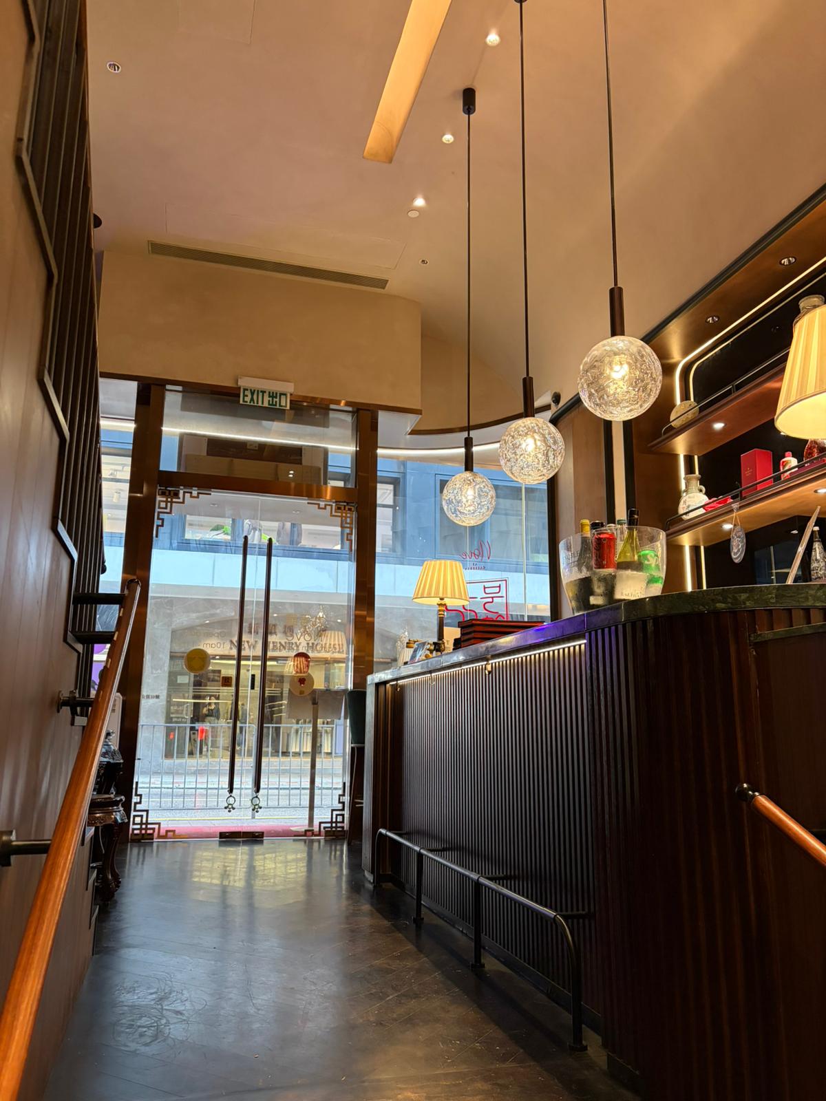 Modern restaurant interior on Queen’s Road Central with hanging lights, wooden counter, and large windows facing the street.