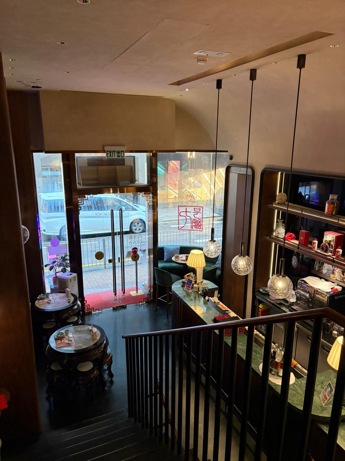 View from a staircase looking over a restaurant in Central with tables, shelves, and windows facing the street.