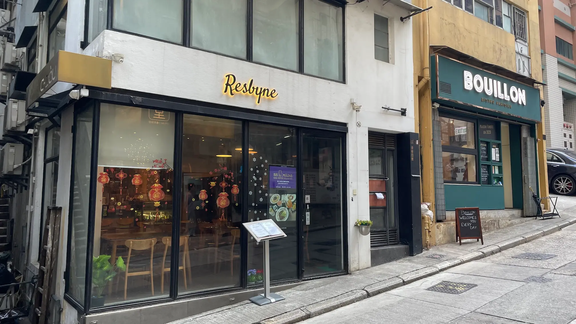 Restaurant space on Pound Lane, Sheung Wan. Respyne and Bouillon glass storefronts along a sloped sidewalk in Sheung Wan.
