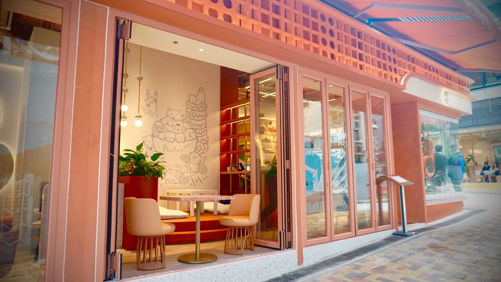 Cafe on Chung Ching Street in Sai Ying Pun with pink chairs, cartoon animal murals, large windows and an open entrance.