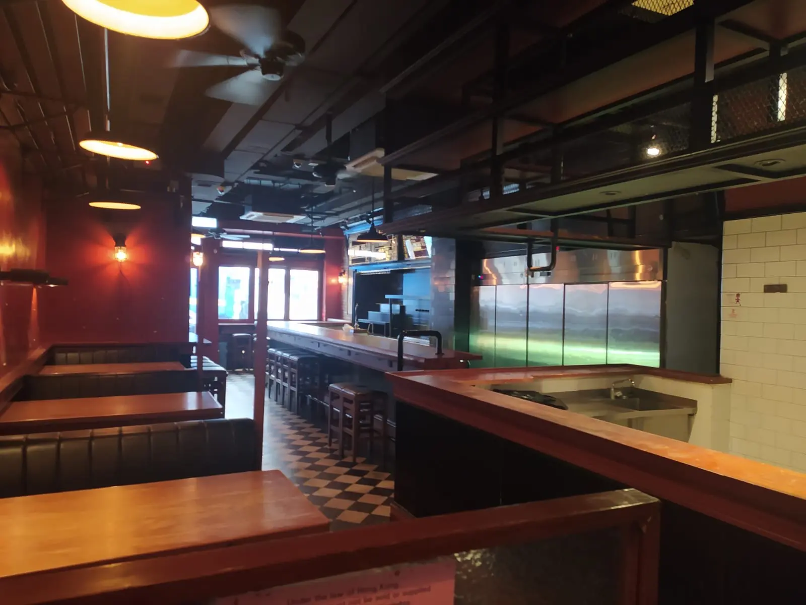 Empty restaurant on Holland Street, Kennedy Town, with wooden tables, black booths, and a checkered tile floor.