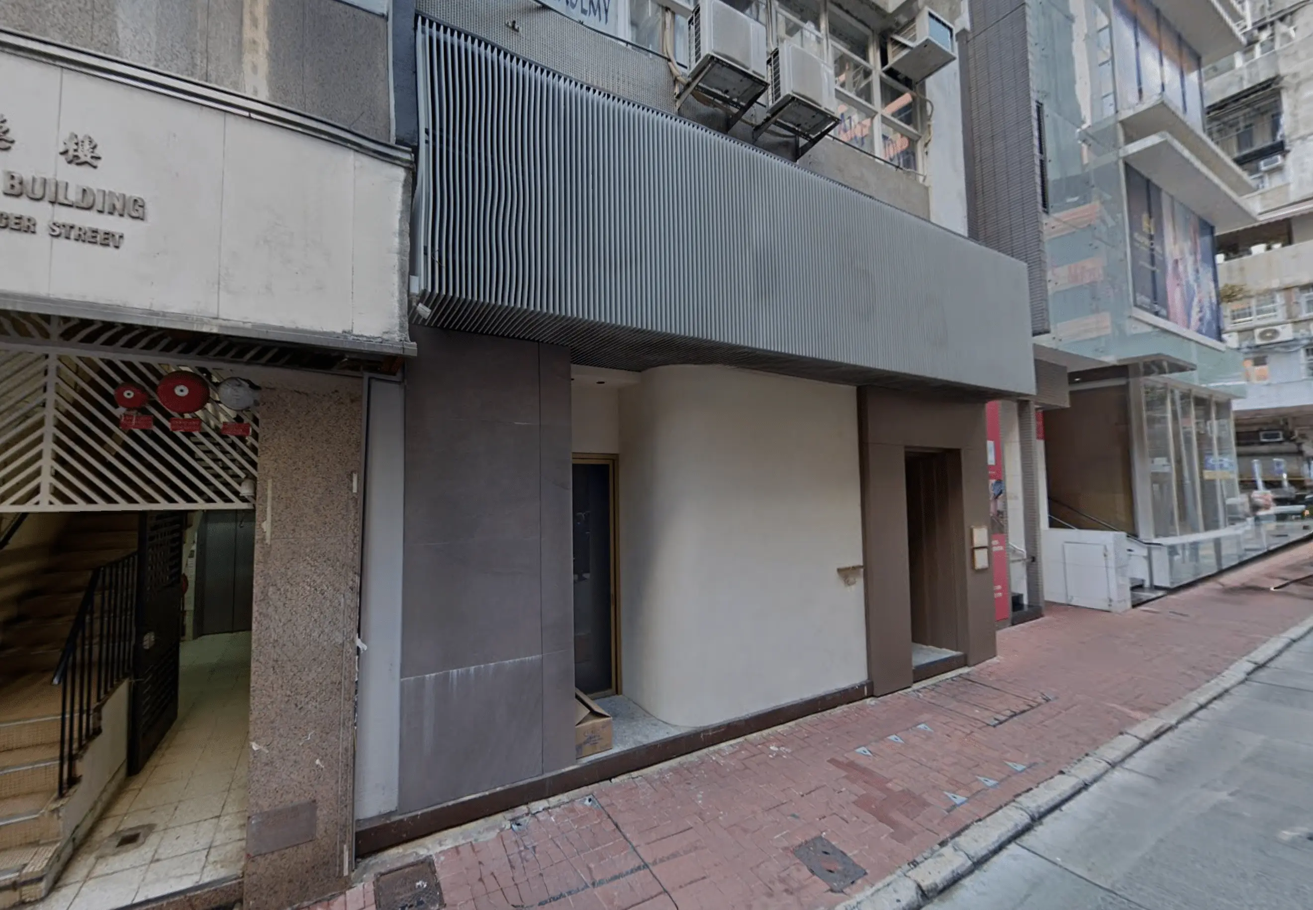 Restaurant space on Mercer Street, Sheung Wan. Closed storefront, next to a building entrance and red brick sidewalk.