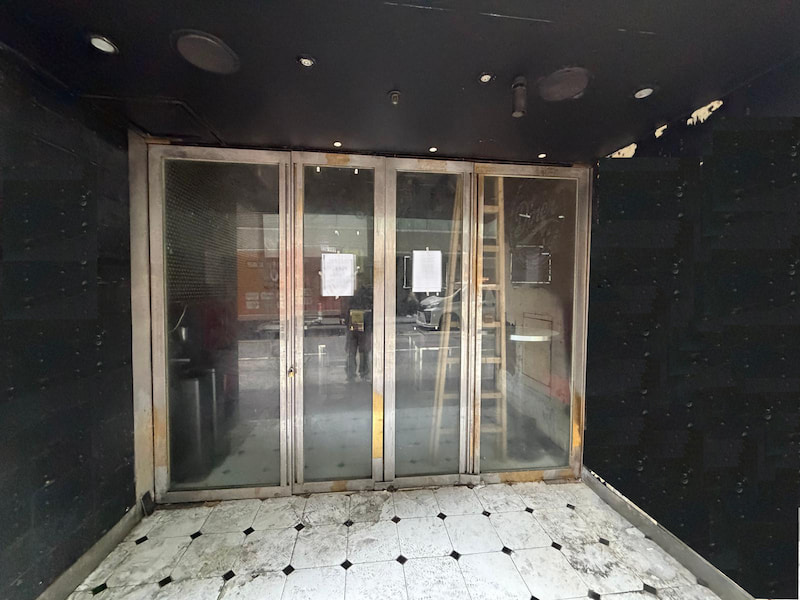 Restaurant space on Wyndham Street, Central. Glass double doors with papers taped on in a dim Wyndham Street entrance, floor tiles appear dirty.